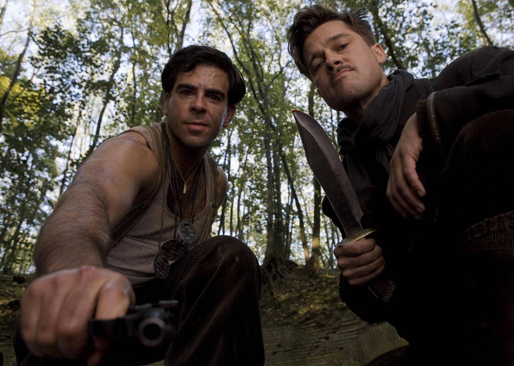 Brad Pitt and Eli Roth holding a gun and knife on someone.
