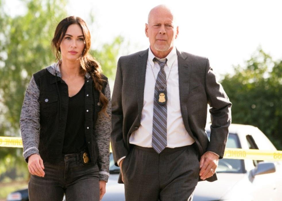 Bruce Willis and Megan Fox walk together with police badges on their hips.