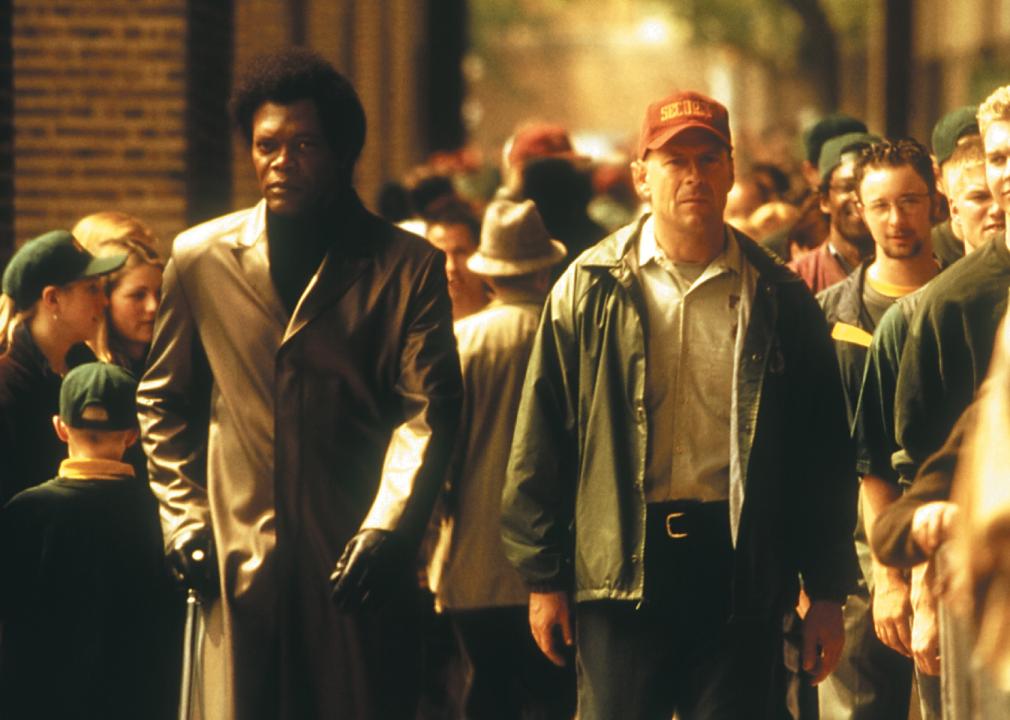 Bruce Willis and Samuel L. Jackson walk through a crowd of people.