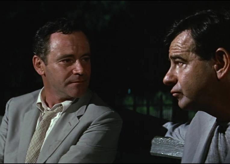Jack Lemmon and Walter Matthau in suits on a park bench at night.