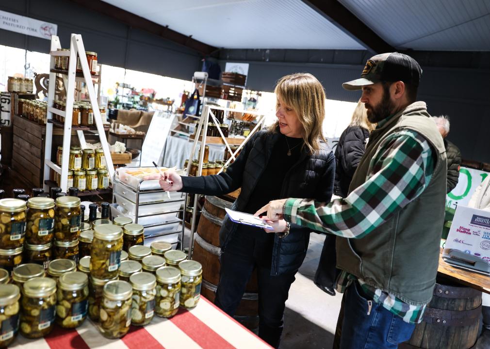 Two owners of a pickle and condiment business check inventory at their booth inside the East End Food Market.
