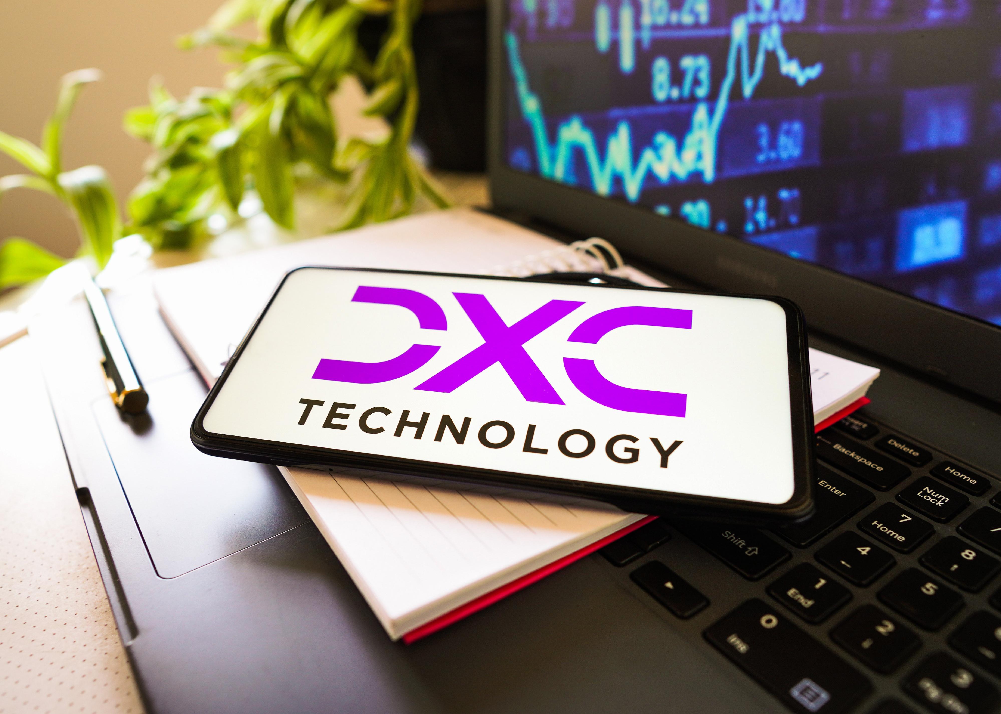 DXC logo on a phone in front of a computer.