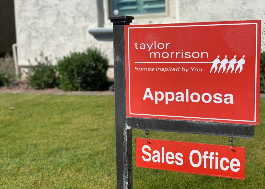 A red Taylor Morrison Homes sign on a lawn.