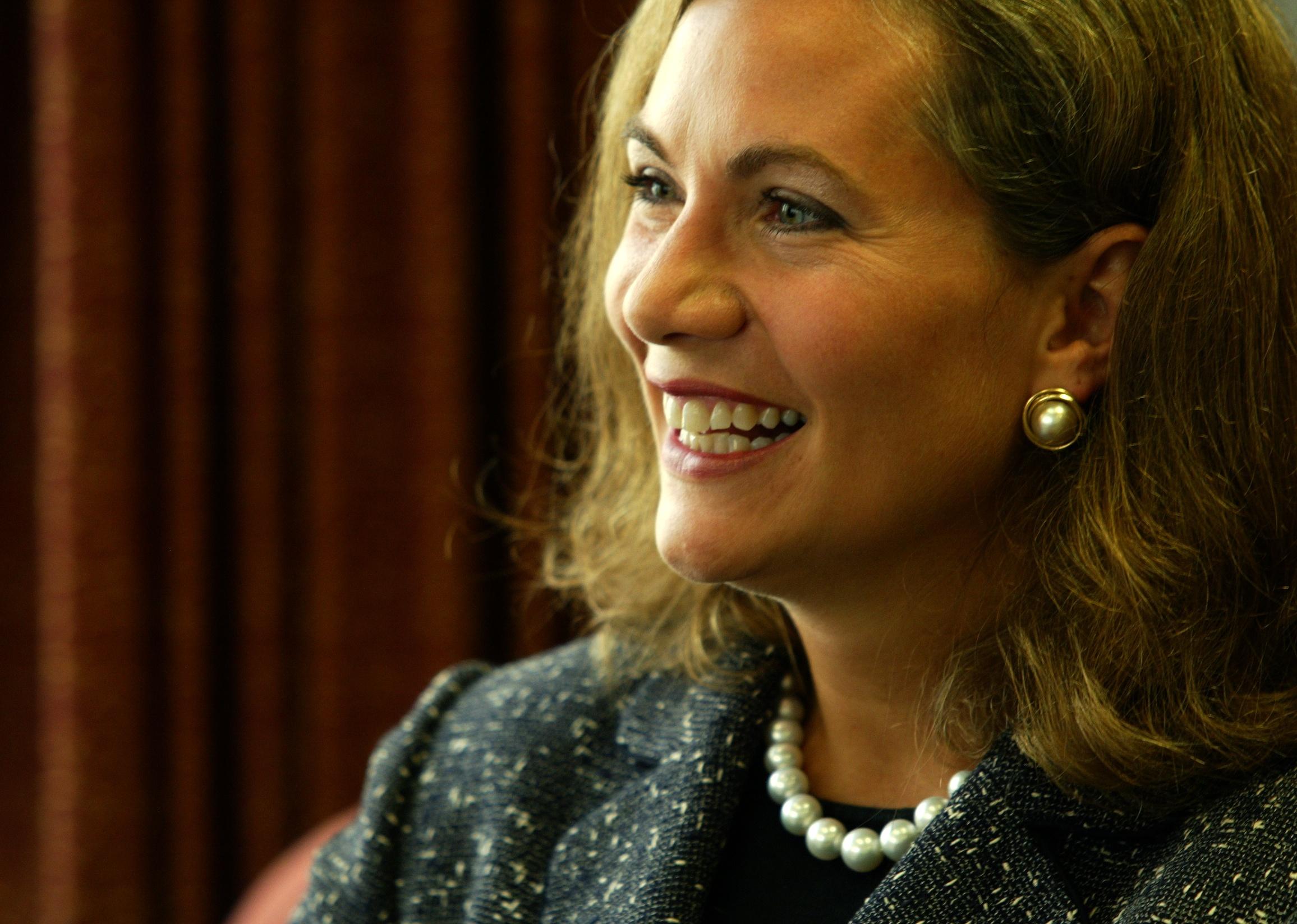 Lori Ryerkerk smiling in a black suit and pearls.