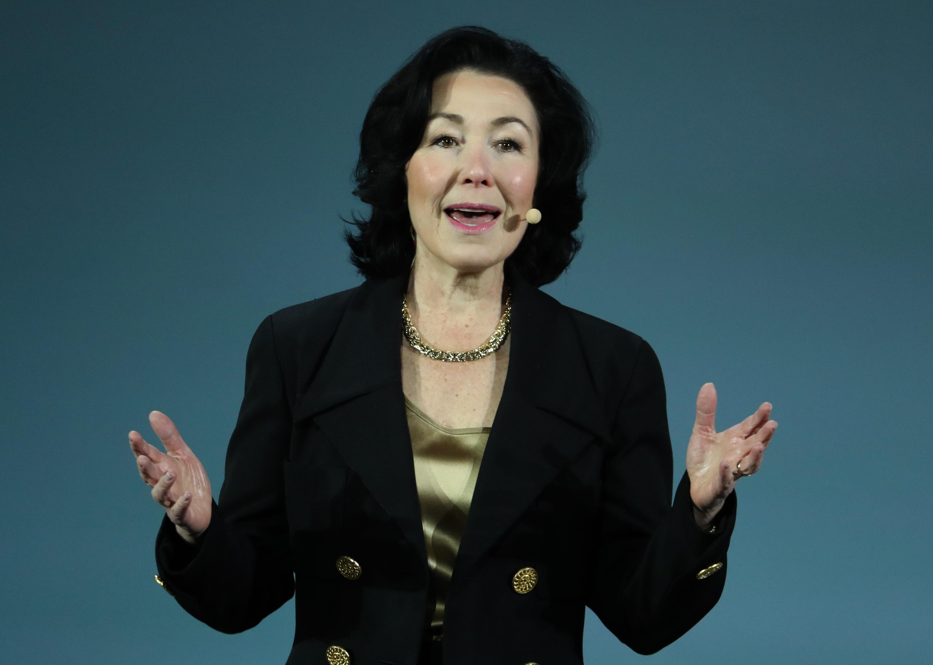 Safra Catz speaking, wearing a black blazer and gold necklace.