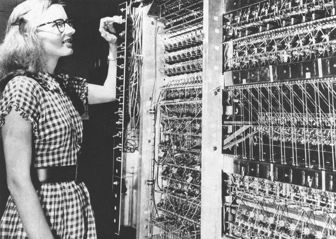 A woman standing next to a calculator taller than herself.