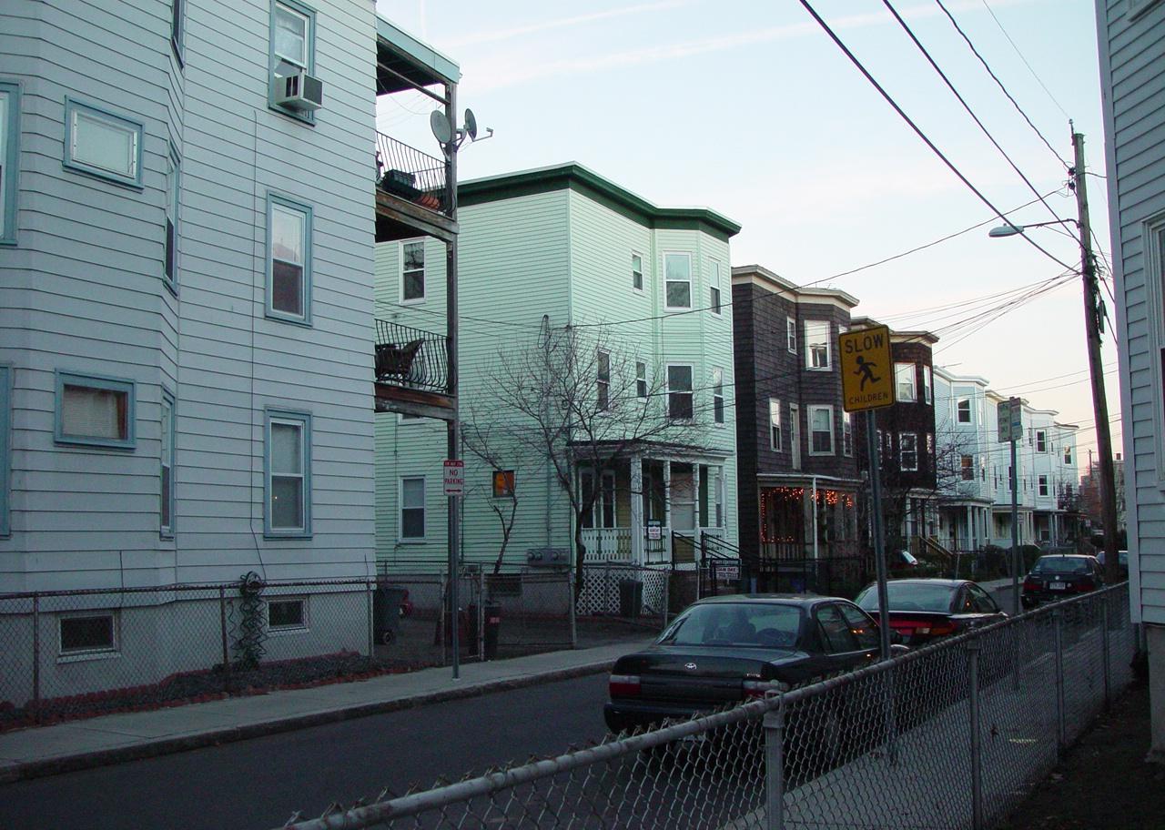 A row of flat-roofed triple deckers in Cambridge, Massachusetts