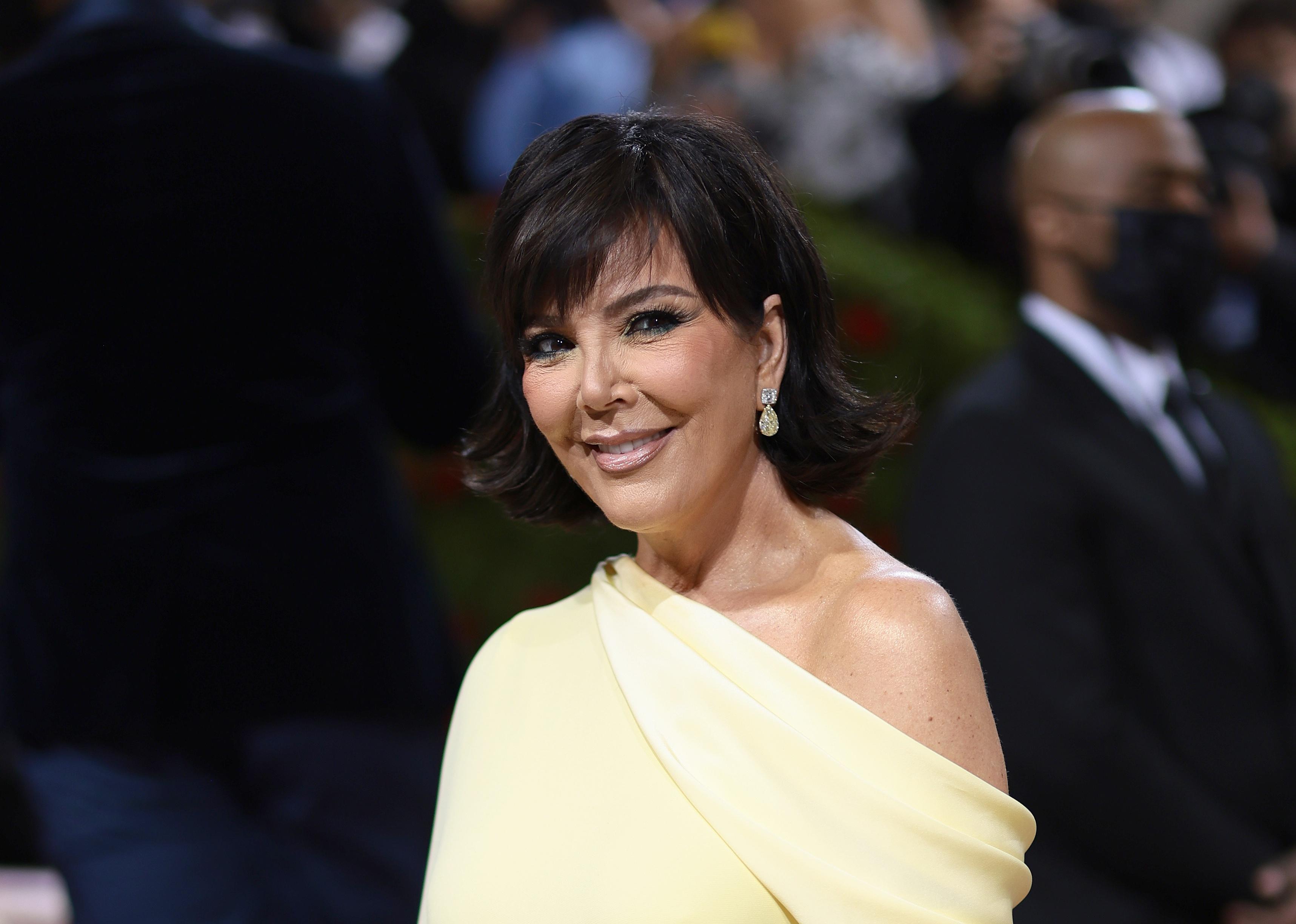 Kris Jenner in a yellow one-shoulder gown.