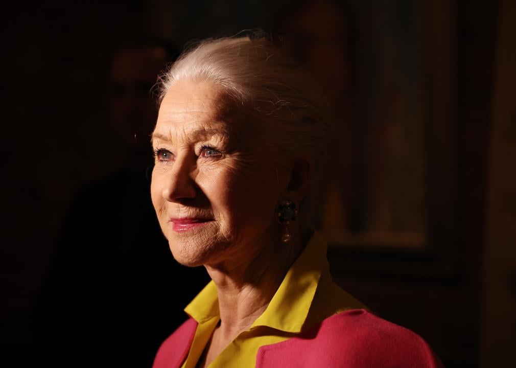Helen Mirren in pink and yellow looking up with light on her face.