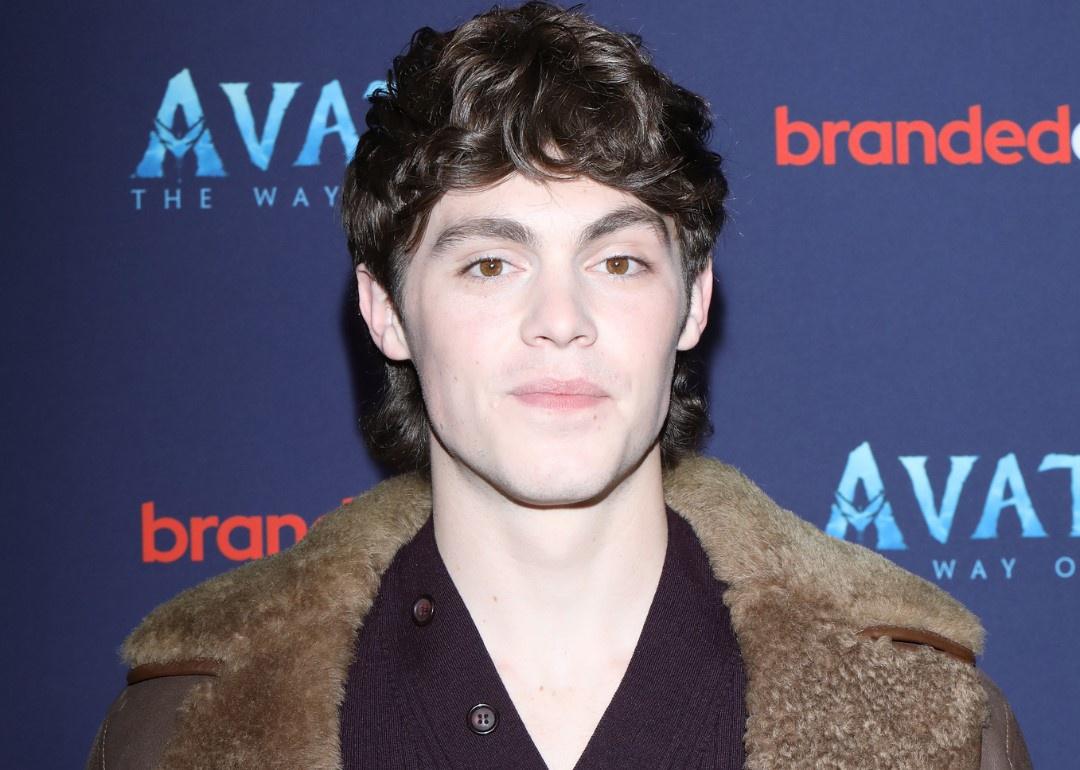 Jack Champion in a brown leather jacket with a fur collar.