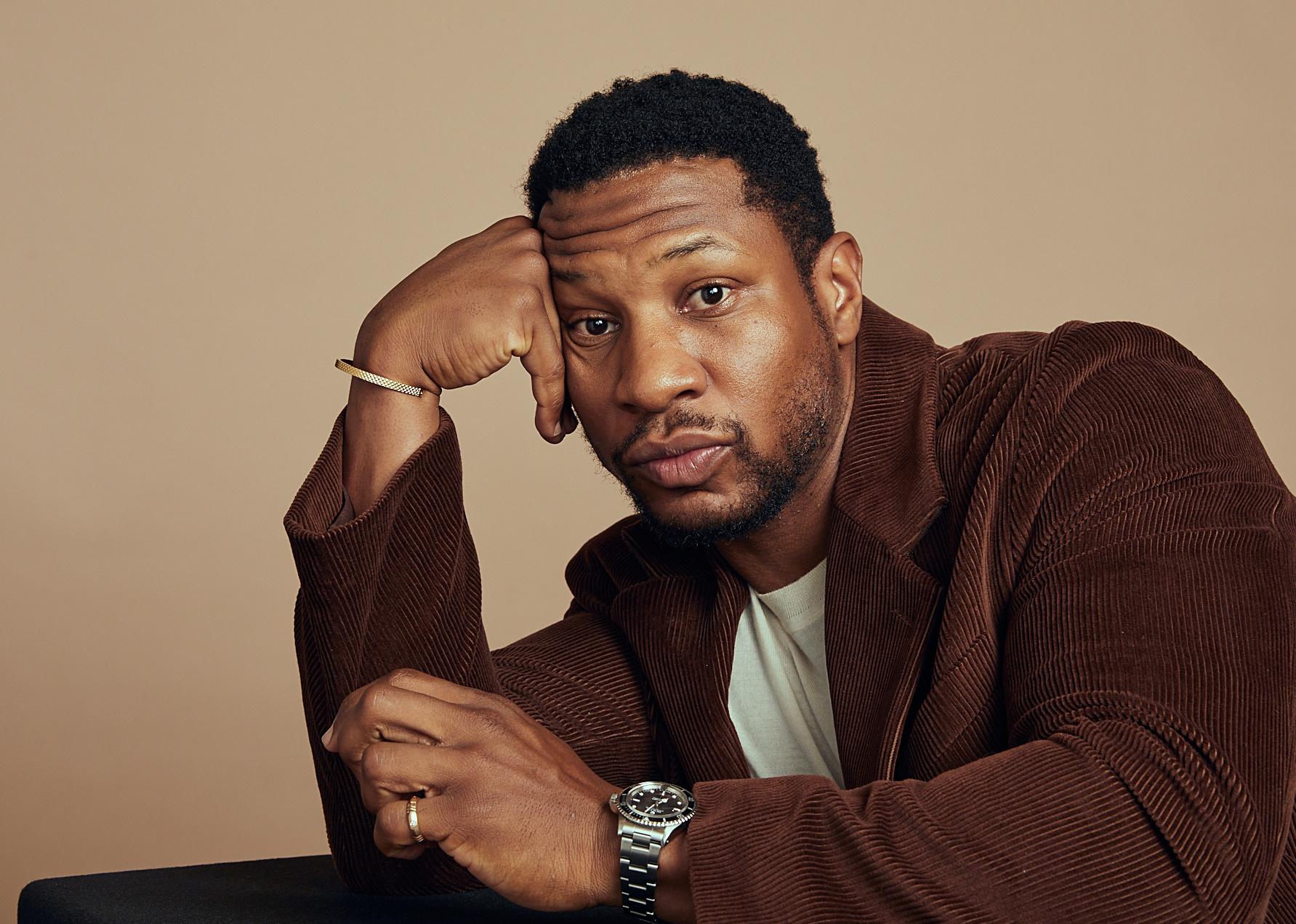 Jonathan Majors posing in a brown corduroy jacket.