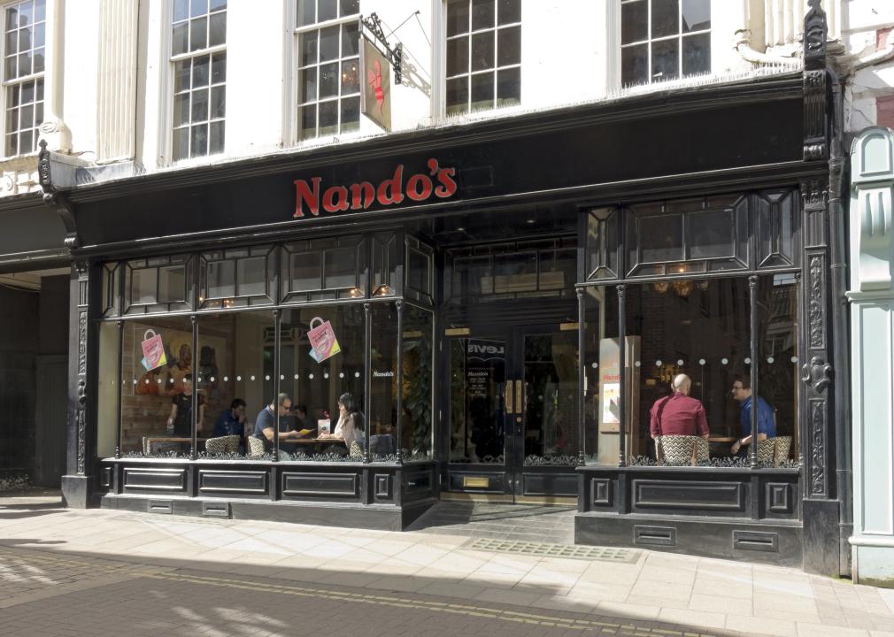 A view of a Nando's from the street, with people dining in near the window. 