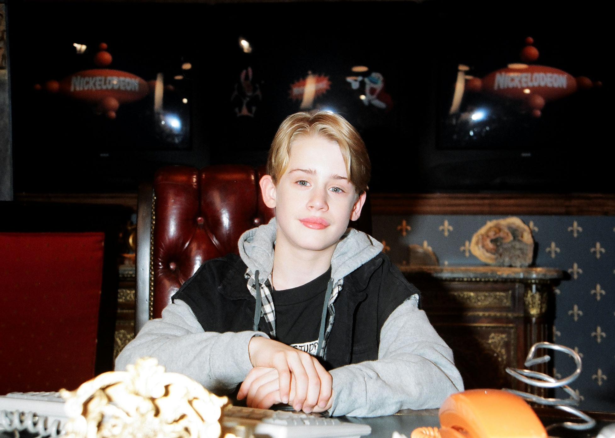 Young Macaulay Culkin sitting at a table at a Nickelodeon event.