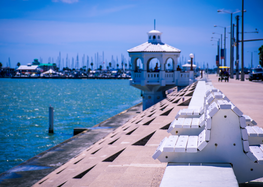 White benches and a gazebo on the water.