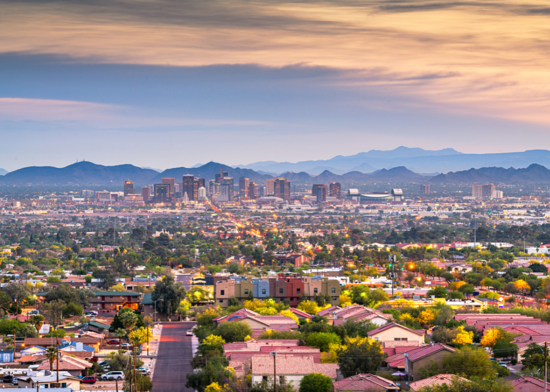 The Phoenix skyline with homes in the foreground and mountains in the background.