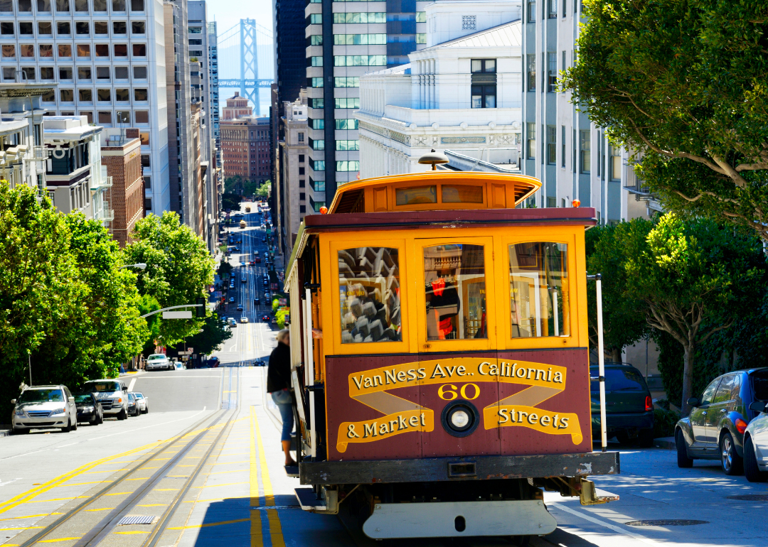 A cable car going down a steep street in downtown San Francisco.