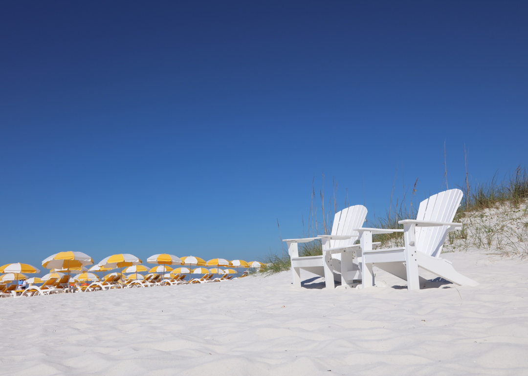Beach chairs and yellow umbrellas on a white sandy beach.
