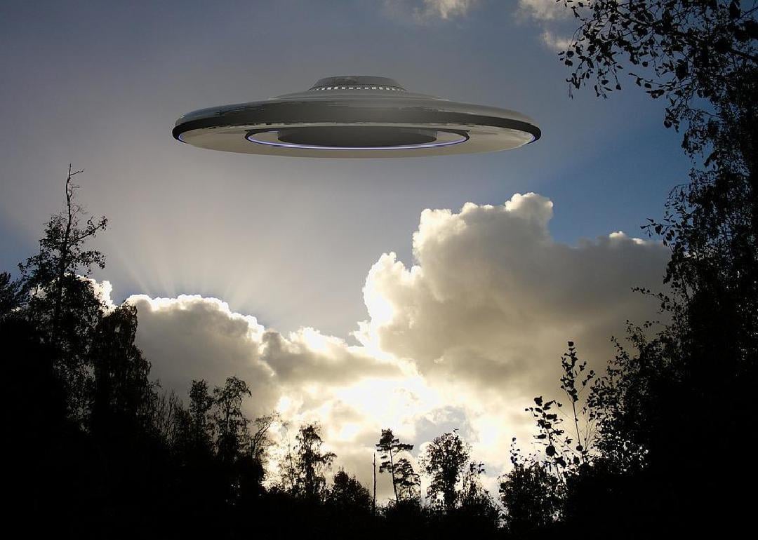 A UFO flying over a wooded area. 