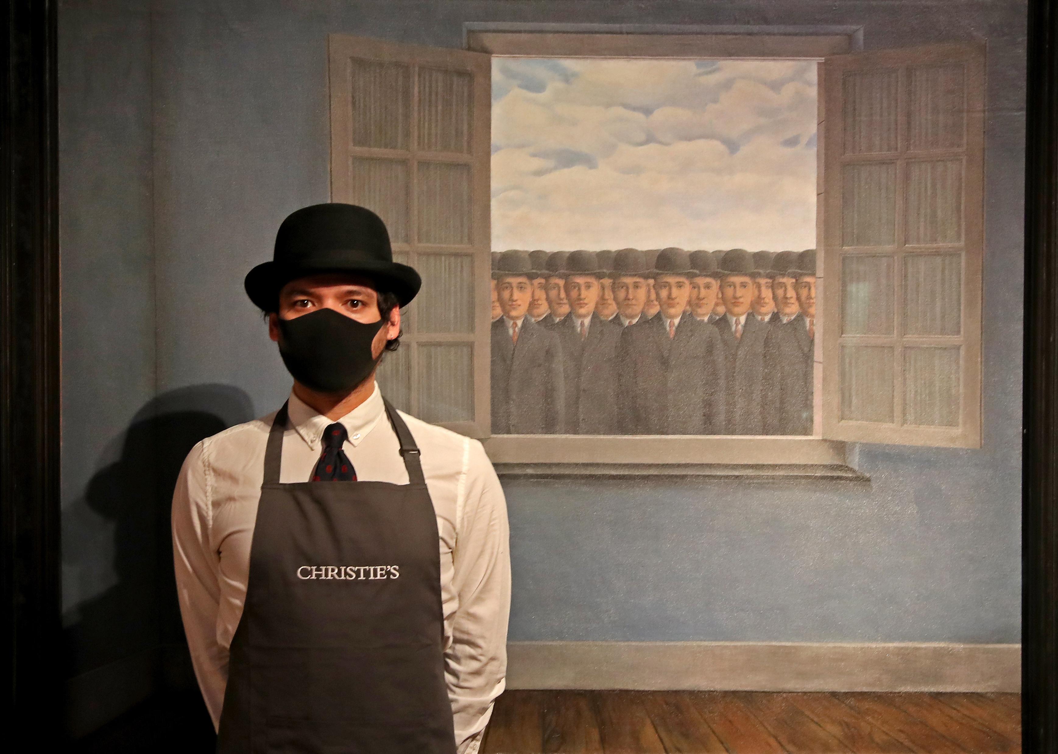 An art worker stands next to Rene Magritte
