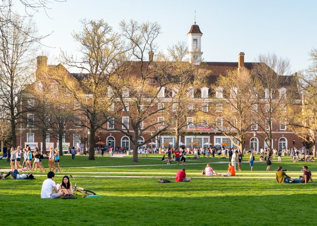 Students sit and study on the lawn of a big university.