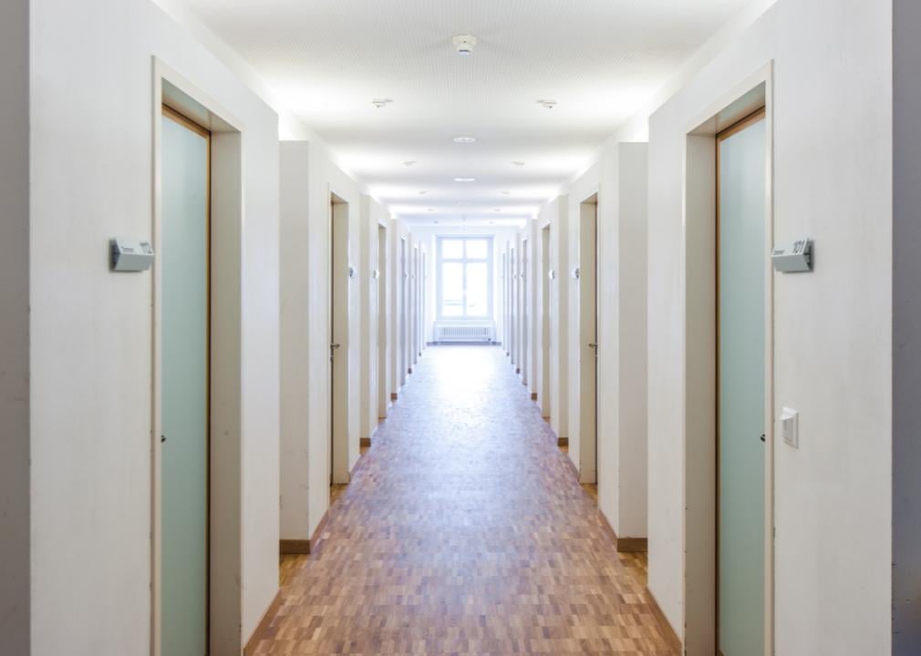Empty hallway of light green dorm room doors.