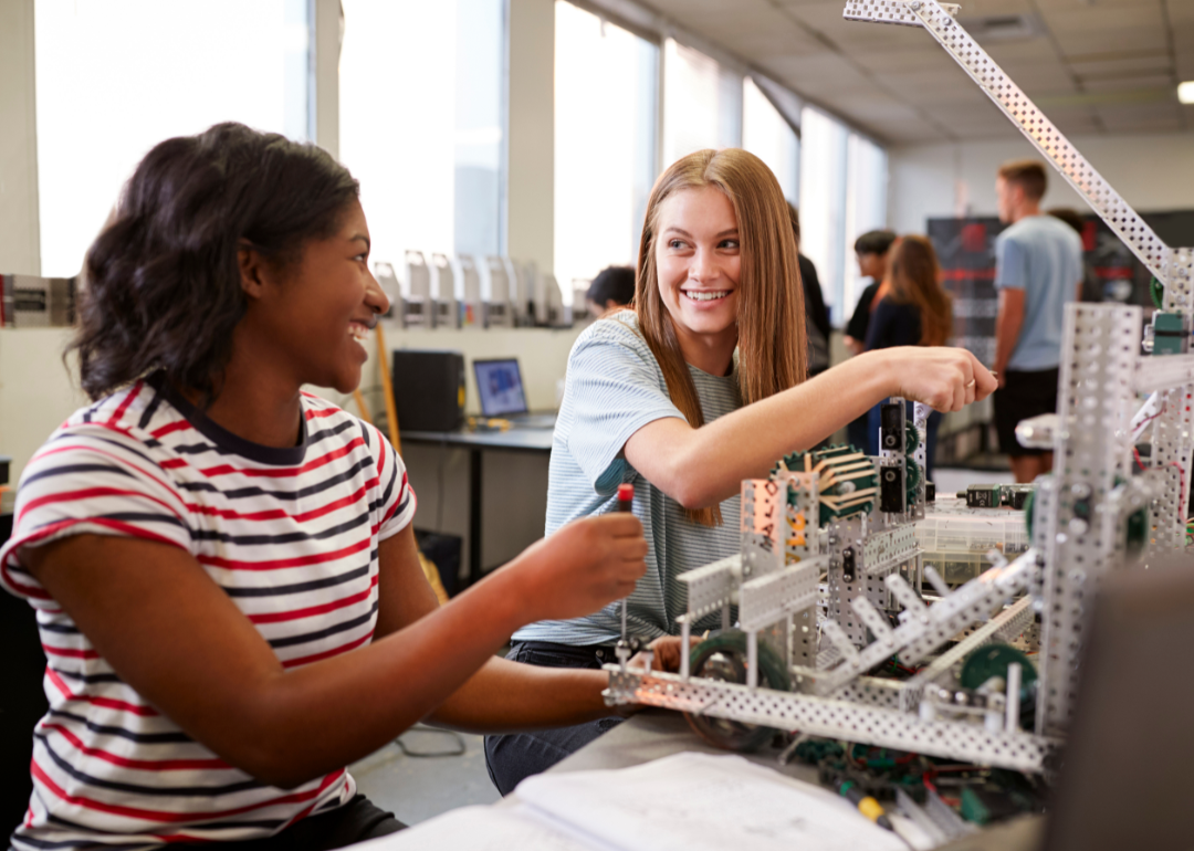Students smiling at each other while building a robot in a college science class
