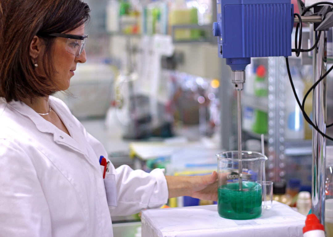 A woman working with a green chemical in a lab.