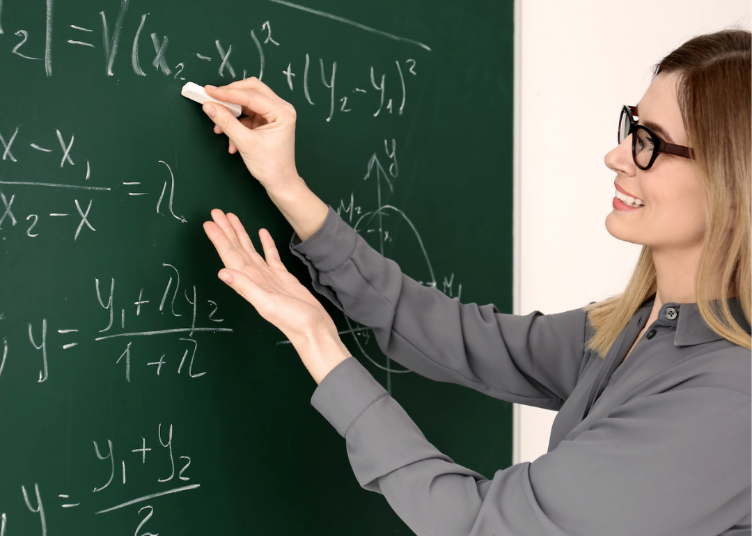 A woman writing formulas on a chalk board.