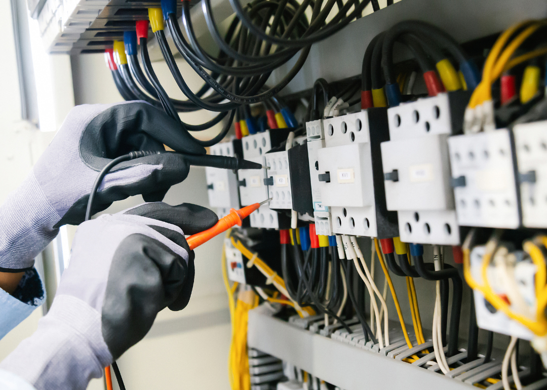 A person wearing gloves testing an electrical installation.