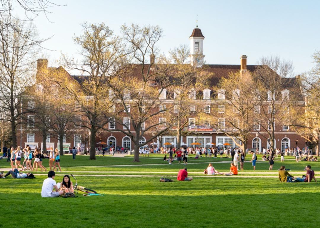 Students sitting on a green lawn in front of University of Illinois.