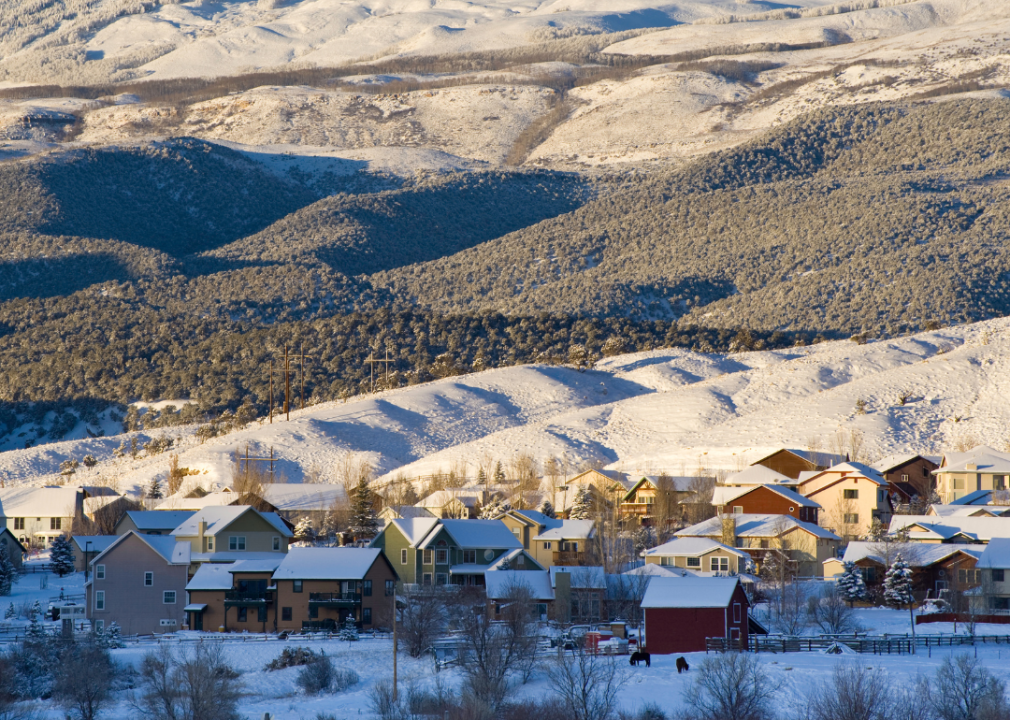 Aerial view of a rural neighborhood positioned among snowy hills. 