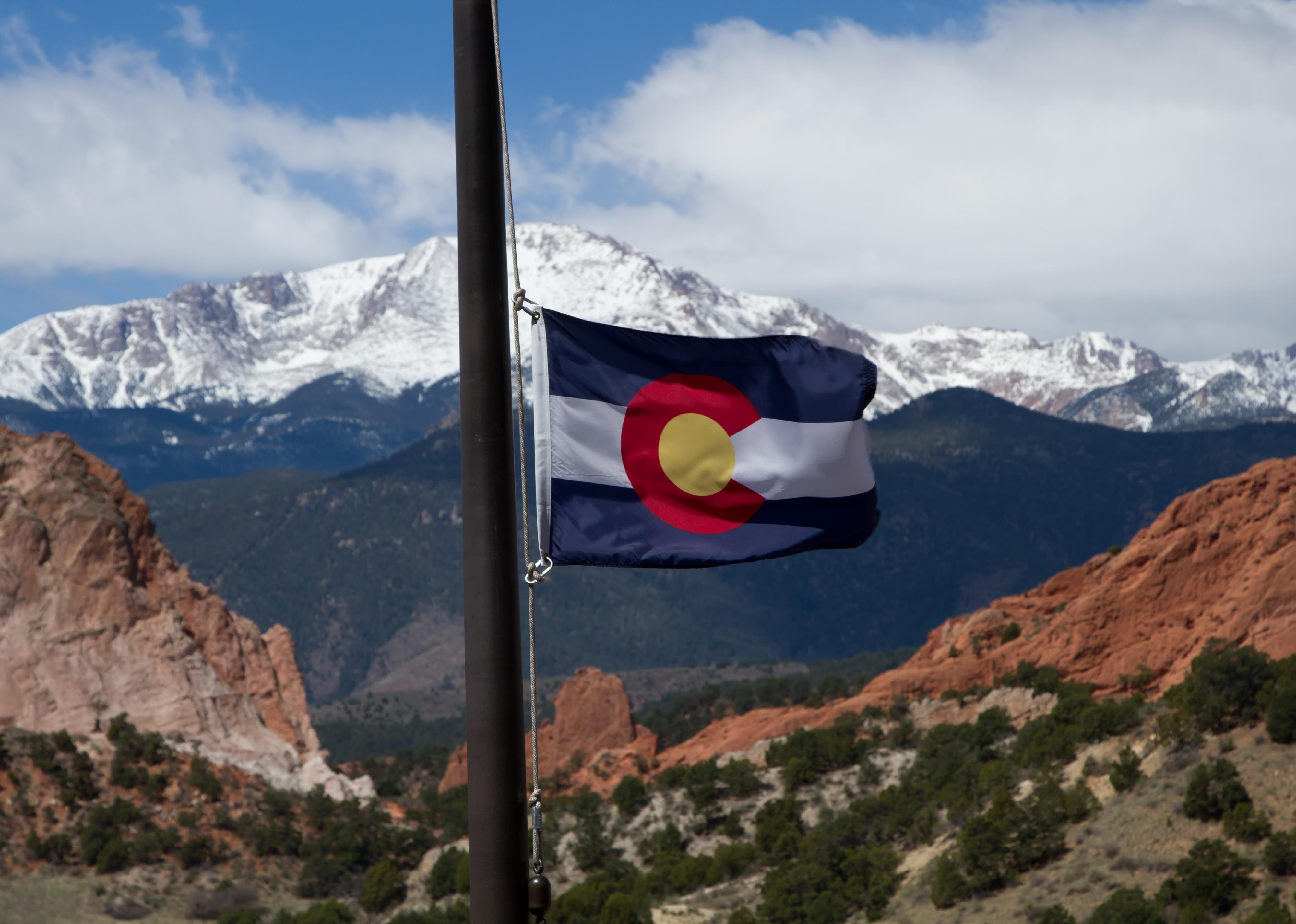 The Colorado flag flies in front of Pikes Peak.