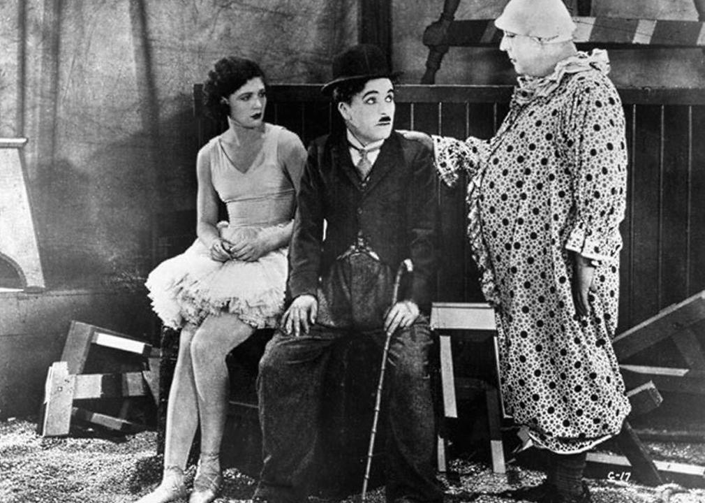 A clown talks with a ballerina and Charlie Chaplin.