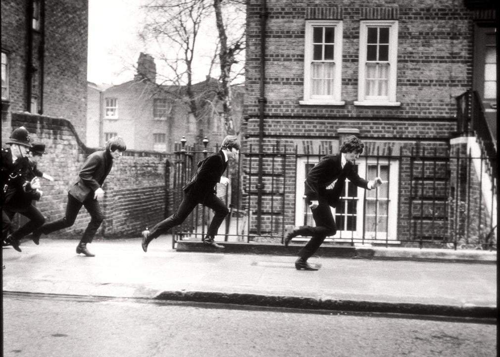 Black and white image of The Beatles running from the police.