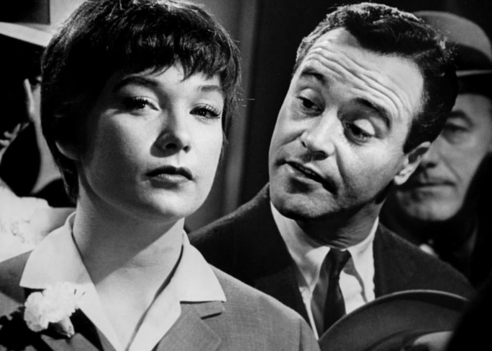 Shirley MacLaine looks ahead while Jack Lemmon talks to her from behind.