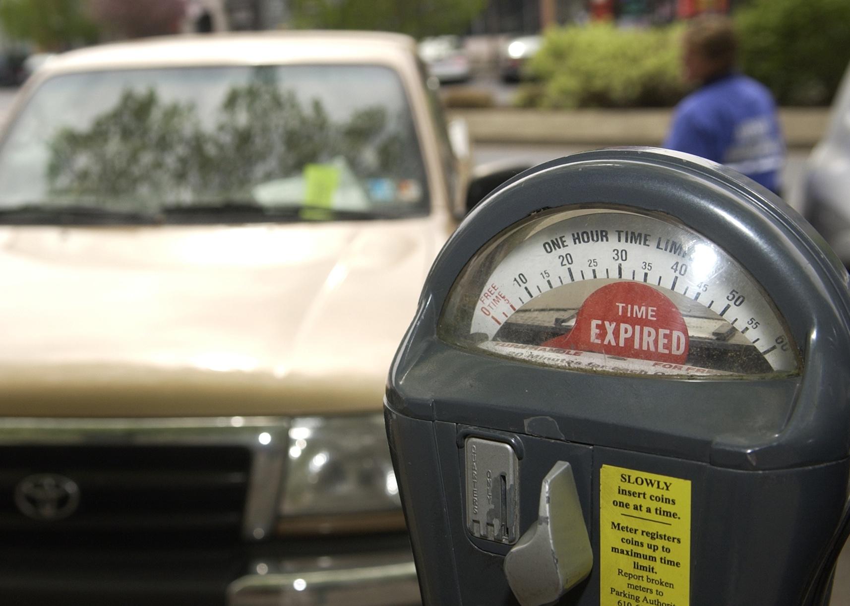 An expired parking meter on the street in front of a truck.
