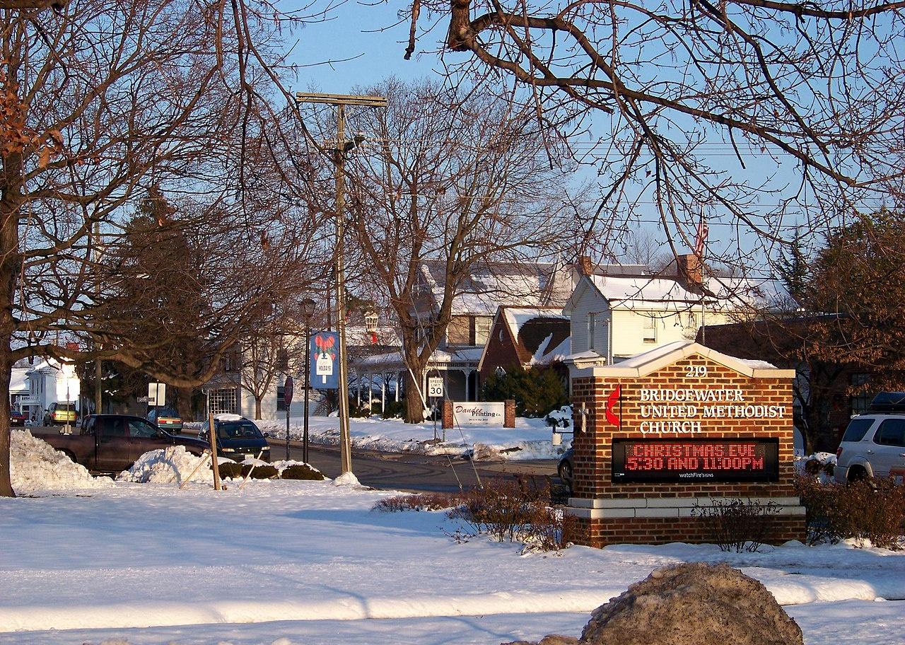 A brick sign for a Methodist church and homes in the snow.