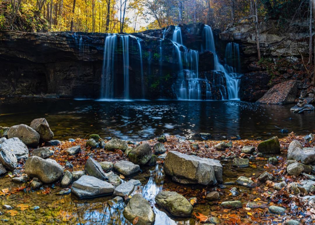 A waterfall coming off of a big black rock in the forest.