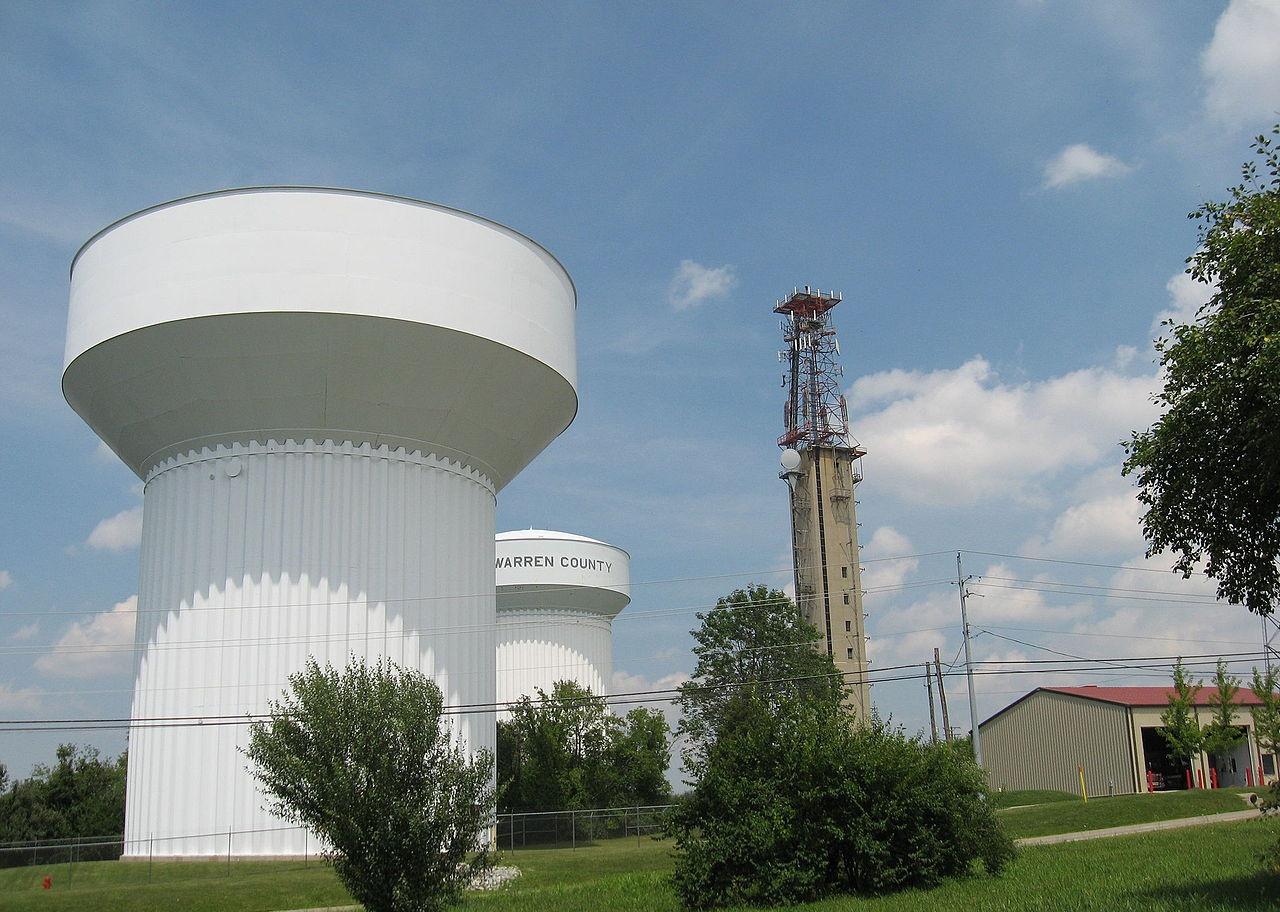 Two large white water towers, an antennae and a building with two open bay doors.