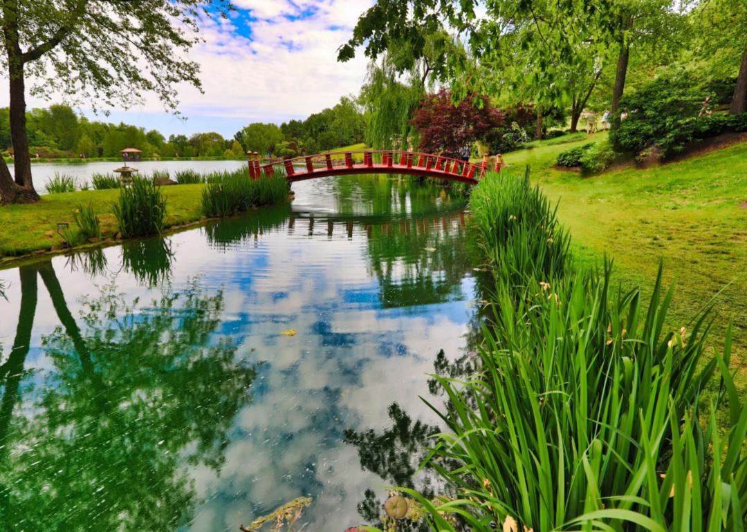 Gardens with a red bridge over water in a park.