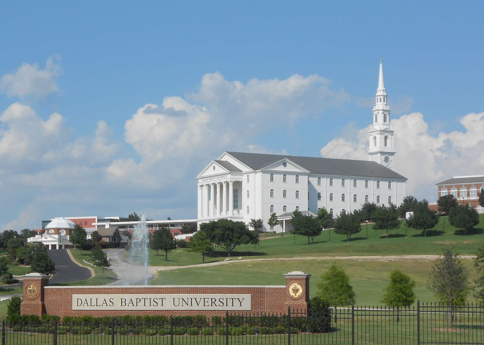 A red brick entrance to a large white building at Dallas Baptist.
