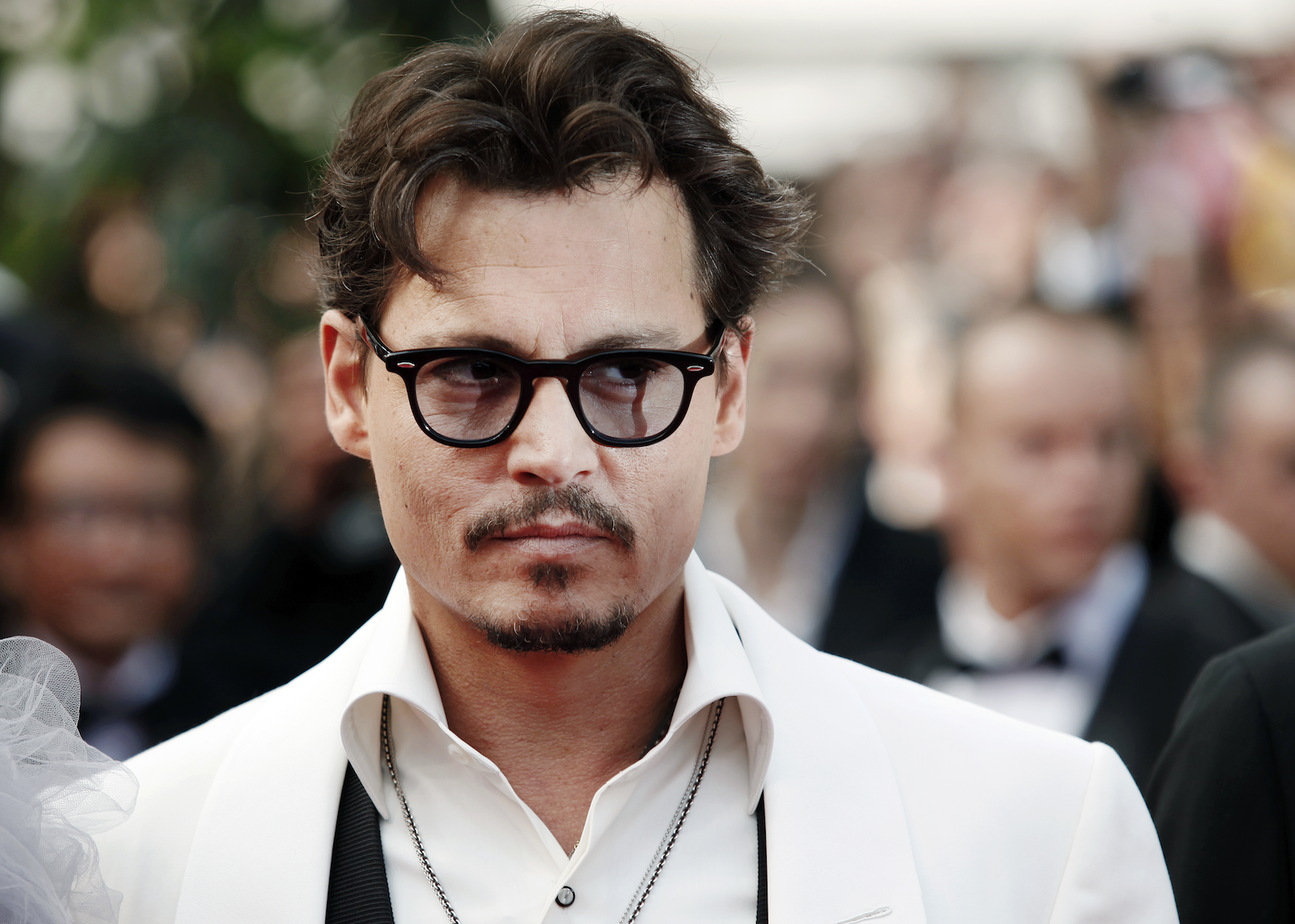 Johnny Depp in a white suit jacket and dark rimmed glasses.