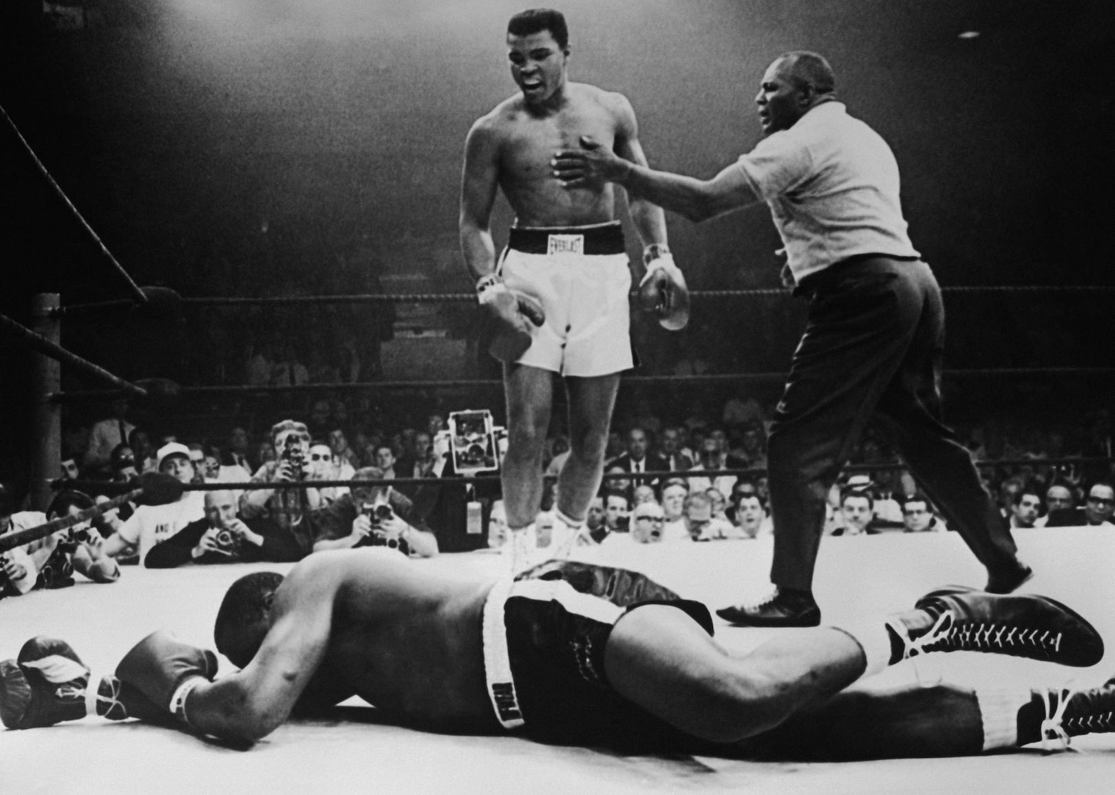 Muhammad Ali hovering over his opponent in the ring.