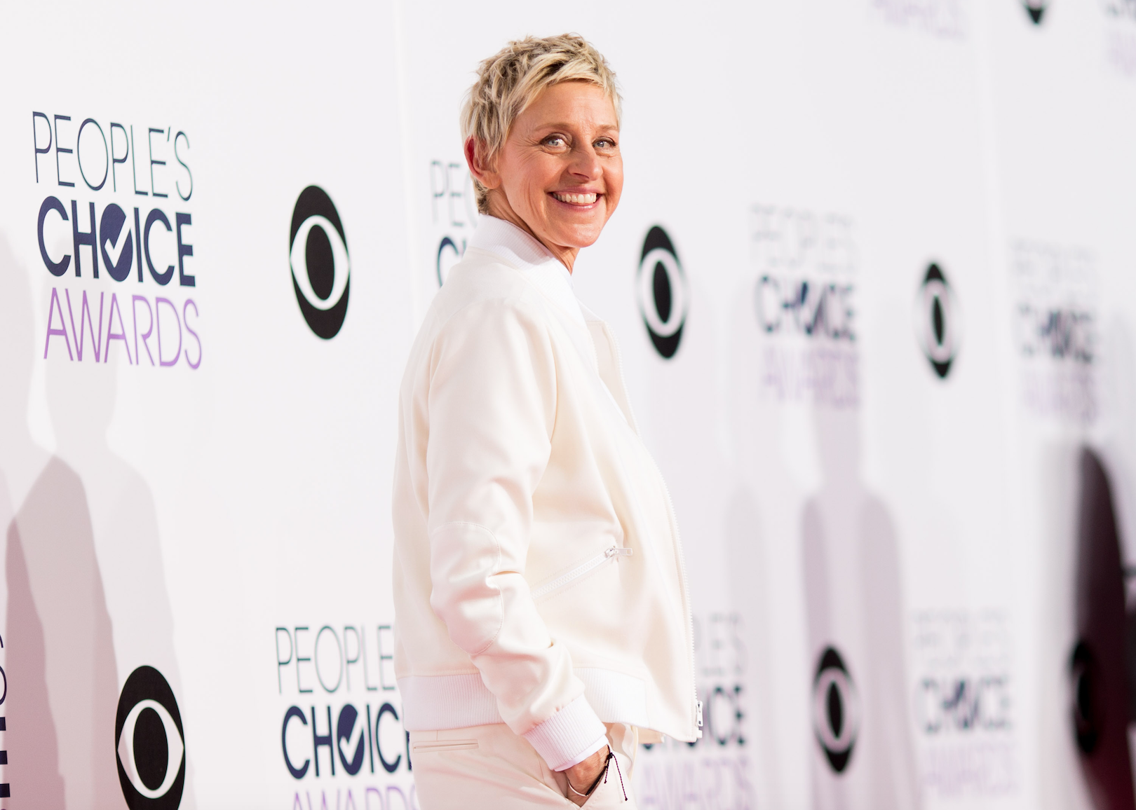 Ellen DeGeneres in all white posing for an event.
