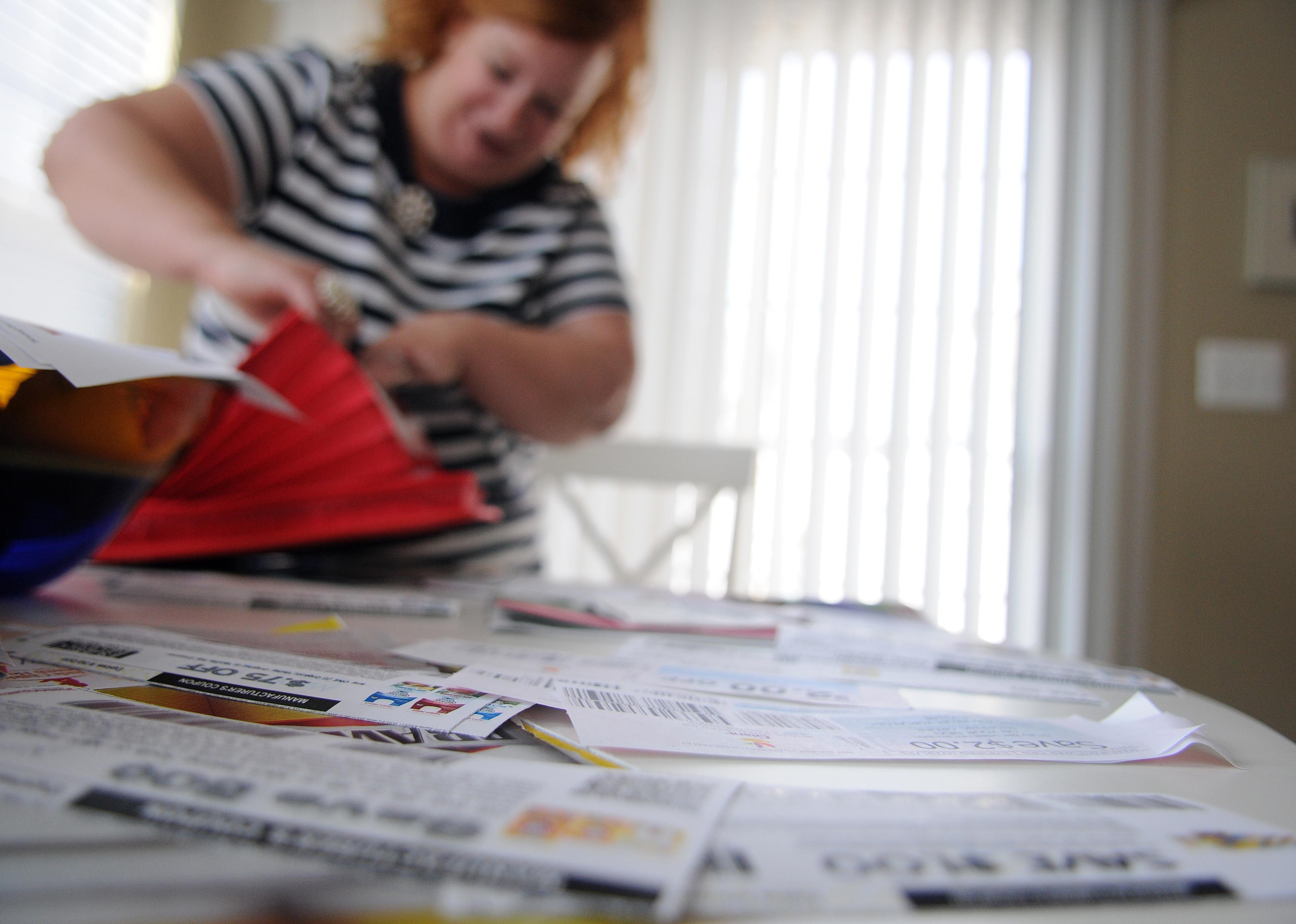 A table full of coupons and a woman blurred out in the background with a folder.