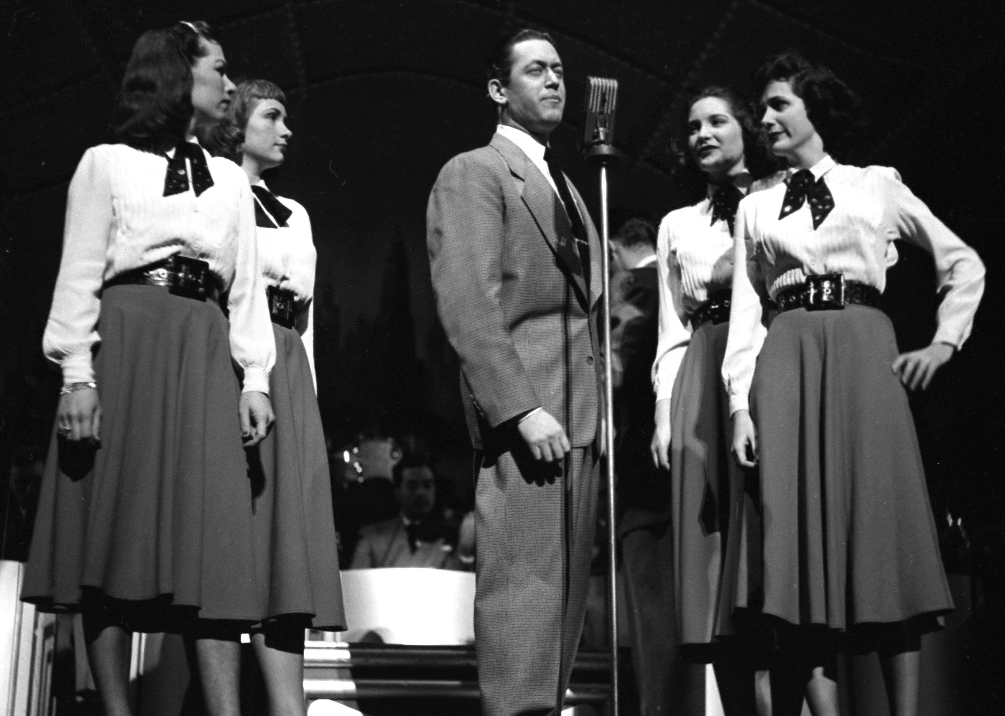 Vaughn Monroe singing onstage with a group of women.