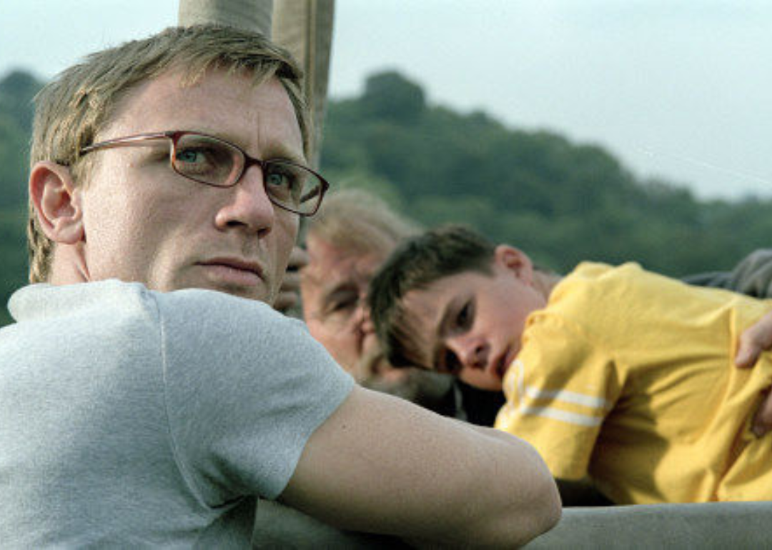 Daniel Craig with a man and little boy in the background.