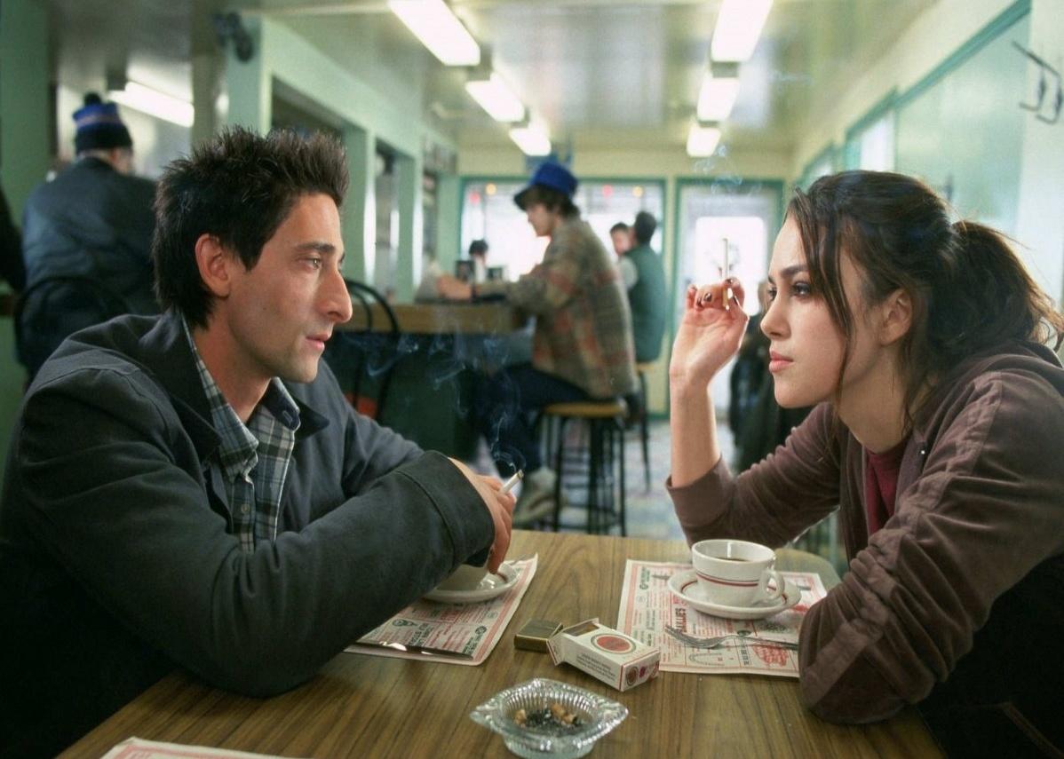Adrien Brody and Keira Knightley smoking cigarettes and drinking coffee at a diner.