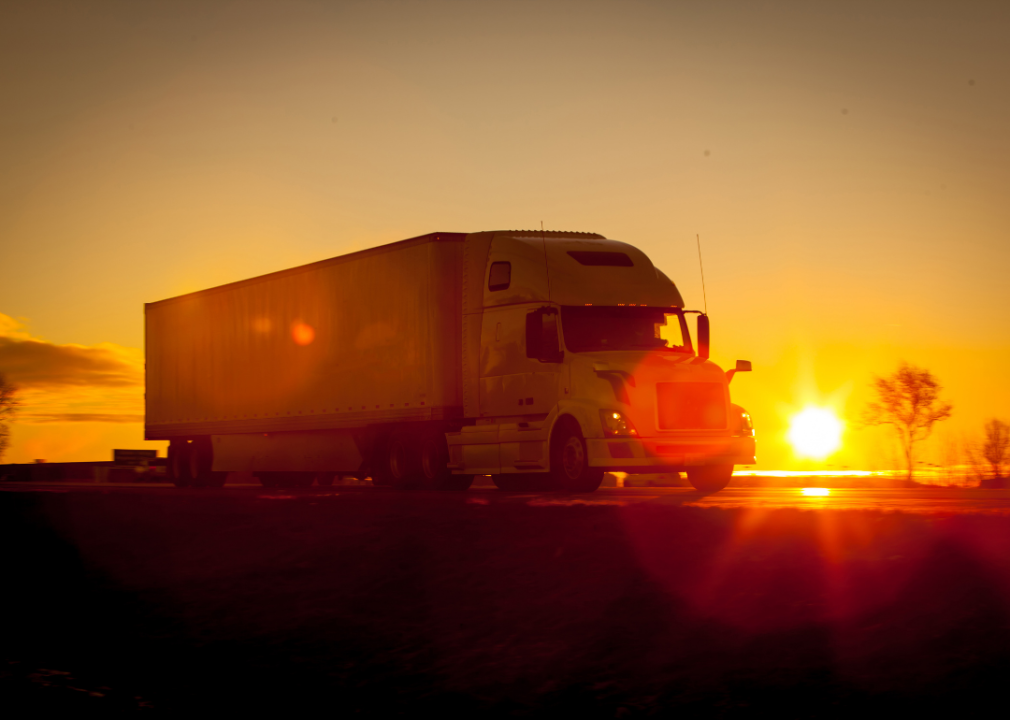 Tractor trailer driving on the highway at sunset.