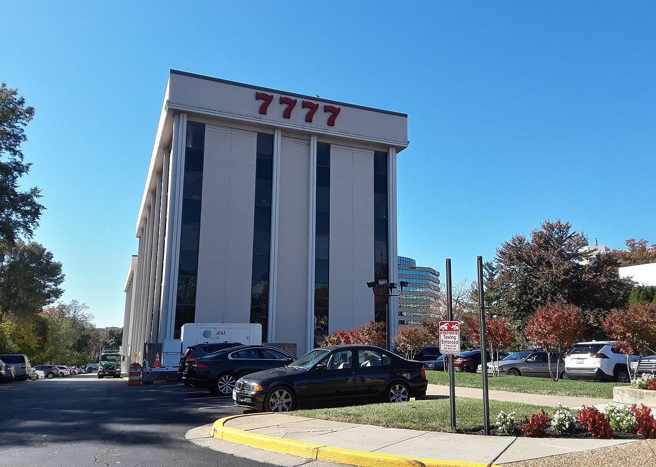 A tall White Stratford University building and parking lot.